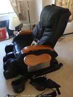 Front three-quarter view showing chair form, wood arm panels, attached tray, plus foot attachments and straps at base