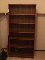 Full front view of the wooden bookshelf showing all five shelves and wood grain finish.