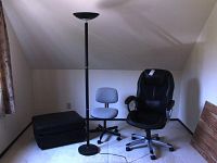 Photo showing the entire lot with torchiere lamp, two office chairs, and black ottoman arranged in a room corner.