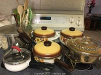Vintage ceramic pots with lids, pressure cooker, glass casserole dish, enamel saucepan on stove
