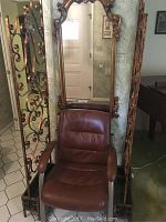 Wide view showing the leather armchair in front of the ornate framed mirror and two decorative wrought iron room dividers.