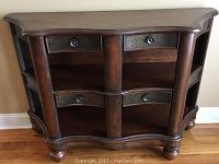 Front view of the wooden display shelf showing 4 drawers with metal decorative details and curved bottom edge.
