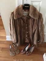 Full view of the vintage leather and mink fur jacket on hanger with two pairs of shoes on floor beneath