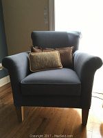 Front view of blue Thomasville armchair with two throw pillows, showing wooden legs and arm shape