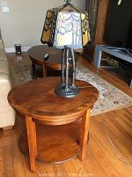 Side table with Tiffany style lamp positioned on top, showing wood finish and inlay design on table surface.