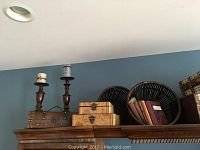 Overview of the full set of old world style decor items arranged on top of a wooden cabinet including wooden boxes, dark stained baskets, candle holders, and books.