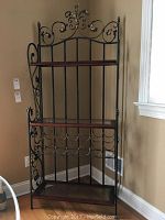 Front view of three-tier ornate metal baker's rack with wine rack