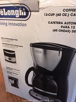 Box showing image and details of the DeLonghi 12 cup coffee maker with digital programmable timer and 60 oz capacity.