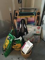 Photo showing two folding beach chairs with metal frames, bags of garden soil, play sand, a black baseball bat, black Schutt baseball glove, a yellow golf ball retriever, watering can, and small terracotta pot with garden supplies.