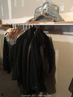 Full view of coats hanging on a clothing rack with hangers visible.