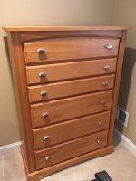 Front view of light wood high boy dresser showing five drawers with silver metal knobs and light wood finish.