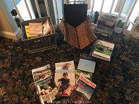 Photo showing the complete collection on a patterned carpet, including the grey plastic magazine rack, wooden tray, and various books and magazines.