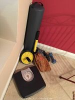 Photo of all items grouped in corner showing scale, ab roller, baseball mitt, dumbbell weight, and yoga mat