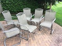 Overview of six matching outdoor patio dining chairs arranged on brick patio, showing general condition and design.