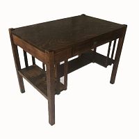 Angled view of the oak desk showing the wood grain and drawer on the front.