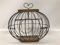 Oval wire birdcage with wooden base and heart-shaped handle on top, shown front view