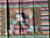 Close-up image showing the detailed Aztec-inspired central figure in the design and striped background.