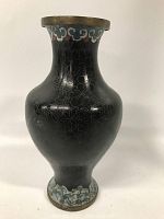 Front view of an antique cloisonné vase showing black enamel with outlined floral designs, metal rim, and decorated base with blue and white patterns.
