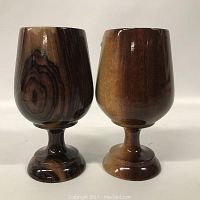 Two turned wooden cups with pedestal bases, showing dark and light natural wood grains, front view