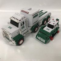 Photo showing two Hess toy vehicles, a large truck and a smaller tractor, both white and green with red wheel accents and chrome details.