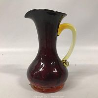 Front view of red to amber gradient art glass pitcher with yellow handle demonstrating shape and color.