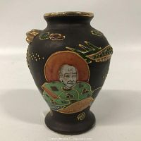 Front view showing older man figure with beard and gold dragon detail on dark brown base.