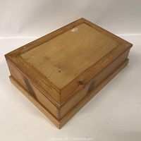 Closed rectangular wooden box with natural finish and dovetail joints on corners.