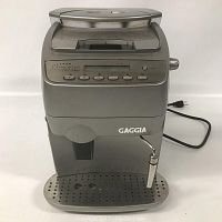 Front view of the Gaggia Syncrony Compact espresso machine showing digital control panel, steam wand, and drip tray.