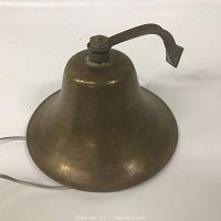 View of the antique brass ship's bell showing the bell and mounting arm on a white background.
