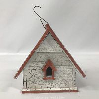 Front view of birdhouse showing crackled white paint, small arched entry with red trim, and red pitched roof with hanging hook.