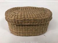 Front side view of the sweet grass woven covered basket with the lid closed, showing oval shape and woven texture.