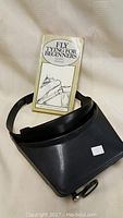 Magnifier with instructional book in protective case on fabric background.