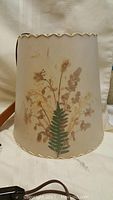 Front view of the cream-colored vintage lamp shade with floral botanical design and scalloped top edge.