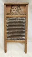 Front view of vintage wooden washboard with metal ribs and printed branding and instructions on the wooden top panel.