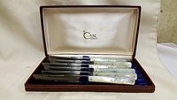 Image showing eight Case steak knives with mother-of-pearl style handles arranged neatly in a velvet-lined case with Case branding inside the lid.