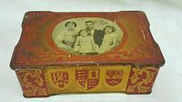 Top and angle views of vintage metal toffee tin with lithograph image of the British Royal Family and ornate detailing