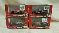 Four die cast NASCAR cars in original packaging, visible front view showing Tony Stewart #20, Mark Martin #8, Kyle Busch #18, and Dale Jarrett #44 models
