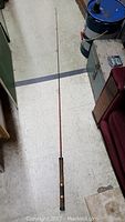 Full length view of the 2-piece fishing rod laid on the floor showing cork handle and rod guides.