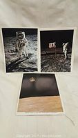 Three vintage moon landing photos arranged on white cloth.