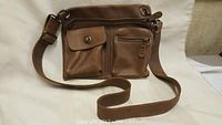 Brown leather handbag purse showing front pockets, strap and closure details