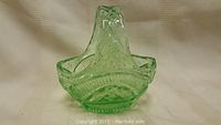 Green depression glass basket front view showing detailed textured design and handle.