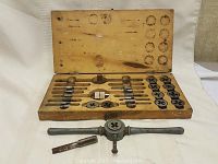 Wooden box open, showing arrangement of taps and dies with some tools outside the box