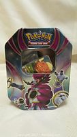 Metal tin decorated with Darkrai and other Pokémon artwork for storing trading cards.