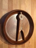 Wooden nutcracker resting inside a round carved wooden bowl on a wood surface.