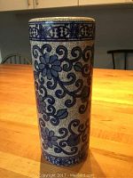Photo of blue and white floral ceramic vase showing decorative vine and flower design on a crackle glaze background.