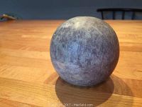 Photo showing the stone orb bowl in a closed spherical form on a wooden table.