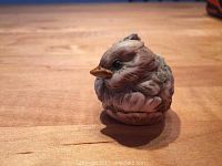 Front angled view of the sleeping bird figurine showing detailed feathers and colors.
