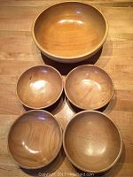 Photo showing all 5 wooden bowls with 1 larger bowl and 4 smaller bowls arranged on a table