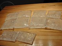 Eight gel-filled clear plastic ice substitute packs laid flat on wood surface, showing contents and size variation.