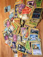 Overview of a large spread of assorted Pokémon cards showing various characters and card backs in mixed condition.